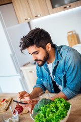 Happy man text messaging on cell phone during breakfast time 