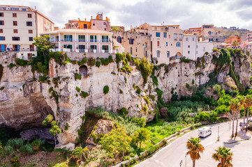 Fototapeta na wymiar Famous sea promenade in Tropea with high cliffs with built on top city buildings and apartments. Parking area on the street. Amazing Italian city