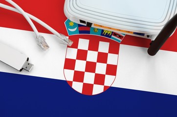 Croatia flag depicted on table with internet rj45 cable, wireless usb wifi adapter and router. Internet connection concept