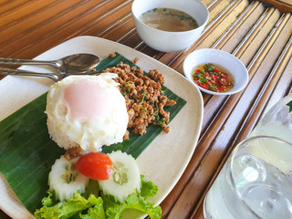 Pork fried rice and fried egg with a drink on a wooden table