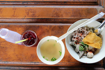 Dry pork noodles with a drink on a wooden table