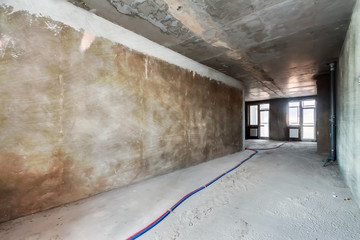 Built structure construction site of residential apartment building. Interior in progress to new house with windows and electric colored wires on the floor in trash colour.