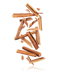 Cinnamon sticks are falling down in chaotic order on a pile on a white background