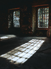A dark atmospheric interior of an abandoned antique space with empty window holes with metal bars...