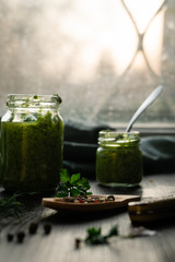 Homemade parsley pesto sauce and ingredients on a windowsill with parsley leaves