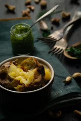 Baked potato with green pesto sauce with cheese