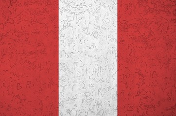 Peru flag depicted in bright paint colors on old relief plastering wall. Textured banner on rough...