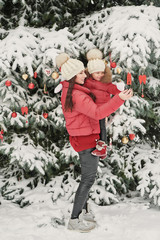 Christmas family in winter park. Happy family mother and child daughter having fun, playing at winter walk outdoors. Outdoor family fun on Christmas vacation.Winter clothing for baby and toddler.
