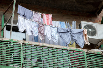 clean underwear and clothes hanging on clothespins on a balcony in a poor area of the city