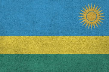 Rwanda flag depicted in bright paint colors on old relief plastering wall. Textured banner on rough...