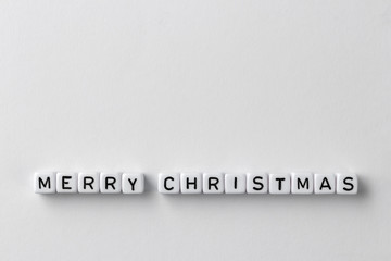 Creative layout of words merry christmas made of wooden or acrylic cubes with letters on white paper background, New Year minimalistic concept