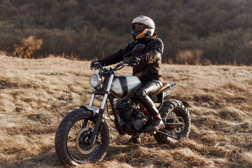 The single man-equipped, motorcyclist drives in the steppe, wearing a helmet, black jacket, gloves, leather pants and boots. Hobby, extreme occupation, recreation in nature, freedom.