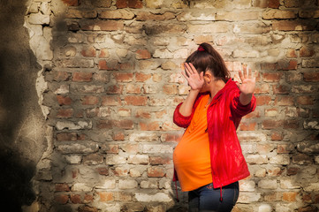 Pregnant woman is afraid. She raised her hands as a sign of protection from fear and negative...
