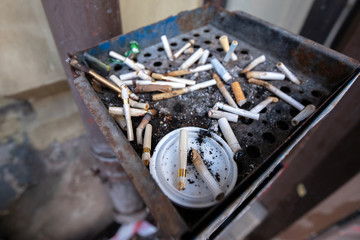 Fototapeta na wymiar dirty rusty street ashtray full of cigarette butts