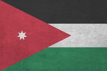 Jordan flag depicted in bright paint colors on old relief plastering wall. Textured banner on rough...