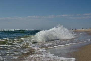Waves with foam at sunny cold Baltic sea beach