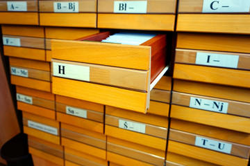 Wooden catalog with an open drawer of letters f and documents in it
