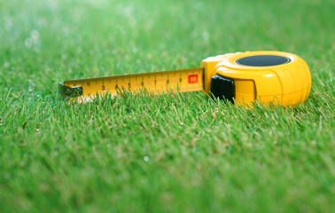 Measuring tape lies on the artificial grass lawn