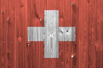 Switzerland flag depicted in bright paint colors on old wooden wall. Textured banner on rough...