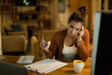 Young worried woman thinking while working in the evening at home.