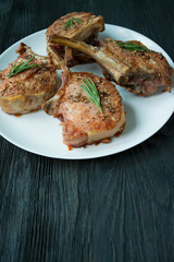 Grilled steaks of pork ribs with spices and herbs. Side view. Dark background.