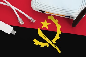 Angola flag depicted on table with internet rj45 cable, wireless usb wifi adapter and router....