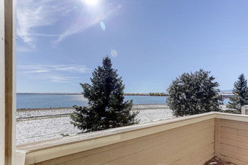 Condominium apartment balcony overlooking pristine lake with dusting of snow on the beach