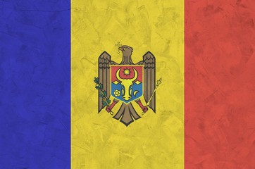 Moldova flag depicted in bright paint colors on old relief plastering wall. Textured banner on...