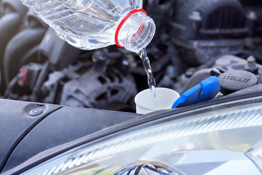 Pouring distilled water (ecological alternative to washing fluid) to washer tank in car, detail on clear plastic bottle