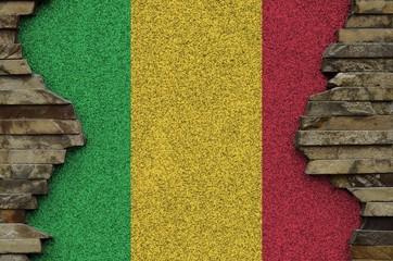 Mali flag depicted in paint colors on old stone wall closeup. Textured banner on rock wall...