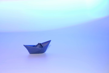 Paper blue ship in an imaginary sea of Periwinkle Color. Copy space.