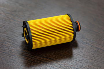 Yellow paper oil filter element on dark background. Auto part. Copy space. Front view from above.