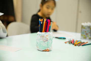 Asian girl drawing color pencils in kindergarten classroom