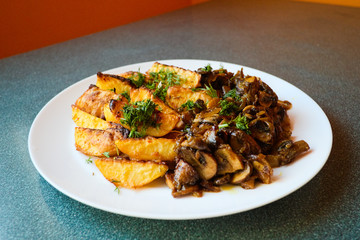 Grilled potatoes with fried mushrooms.Served in white plate. Selective focus