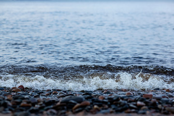 Fototapeta na wymiar Coastal wave on the rocky shore of the lake