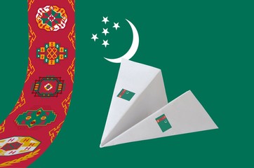 Turkmenistan flag depicted on paper origami airplane. Handmade arts concept