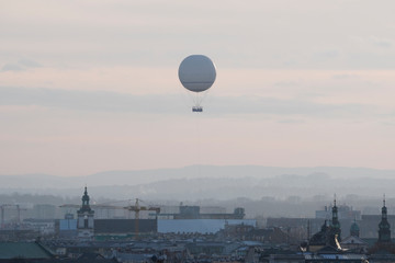 a white balloon flies over the old town in foggy weather in Krakow. attraction for tourists, flying over the city. stone jungle with a bird's eye view.