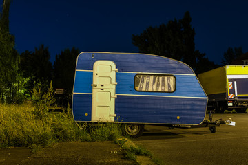 Small caravan in a parking lot, A small blue caravan at night
