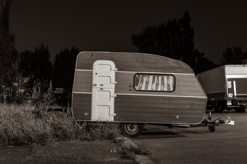 Small caravan in a parking lot, A small caravan at night, black and white photo