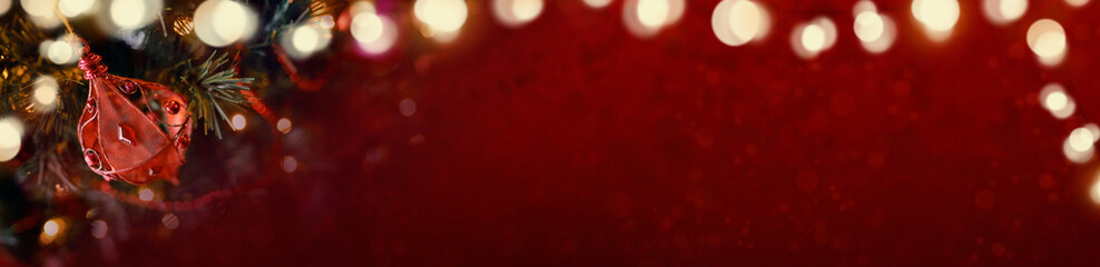 Red Christmas banner of tree decorations and glowing lights on a blurred festive background.