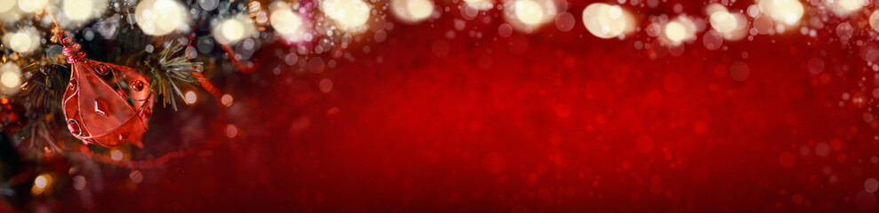 Red Christmas banner of tree decorations and glowing lights on a blurred festive background.