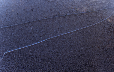 Fototapeta premium Frost on the window. Beautiful frosty pattern on the cracked window. Patterned snow on the broken glass. Winter frost wallpaper