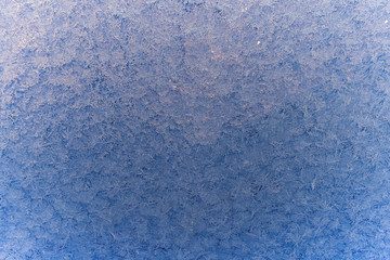 Texture of snow-white snowflakes on transparent glass. Beautiful frosty pattern on the window. Winter wallpaper frosty snowflakes on the glass.
