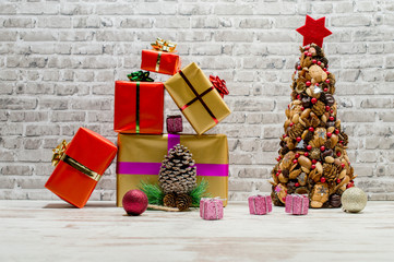 Christmas still life on white oak table with brick background.Atypical Christmas tree made from fruits of forest. Gifts and packages tied with ribbon and bow.