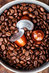 Espresso coffee capsules or pods and coffee beans on wooden rustic background, top view