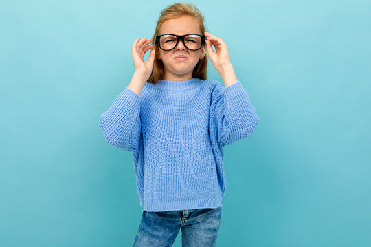 cute european girl squinting in glasses on a light blue background