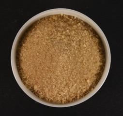 brown sugar in a bowl isolated on black background