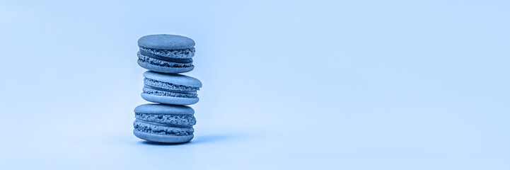 Fototapeta na wymiar Banner with three macaroons toned on blue background with copy space.