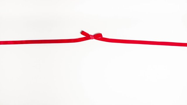 Red velvet ribbon tied in a gift bow on white background with copy space. Stop motion animation holidays  and partys concept