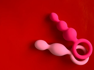 Pink two anal plugs on red background. Useful for sex shop or adults